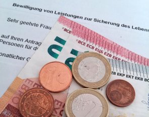 Sozialleistungen Foto zeigt Geldmünzen und Scheine