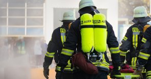 Brand - und Katastrophenschutz Feuerwehrleute, die mit einem Spineboard zum Brand laufen