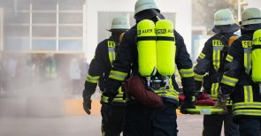 Brand - und Katastrophenschutz Feuerwehrleute, die mit einem Spineboard zum Brand laufen