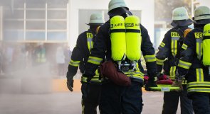 Brand - und Katastrophenschutz Feuerwehrleute, die mit einem Spineboard zum Brand laufen