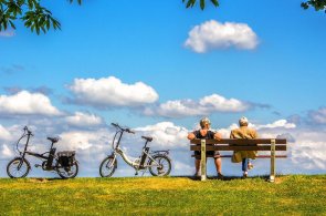Öff. Personennahverkehr Frau und Mann auf einer Parkbank und Fahrräder
