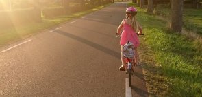 Schulweg Kind mit Fahrrad und Ranzen auf einer Straße