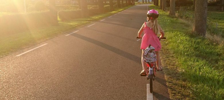 Kind mit Fahrrad und Ranzen auf einer Straße